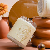 Hand-poured soy wax Aries candle from Wax Crescent, displayed with earthy decor and a single orange flower