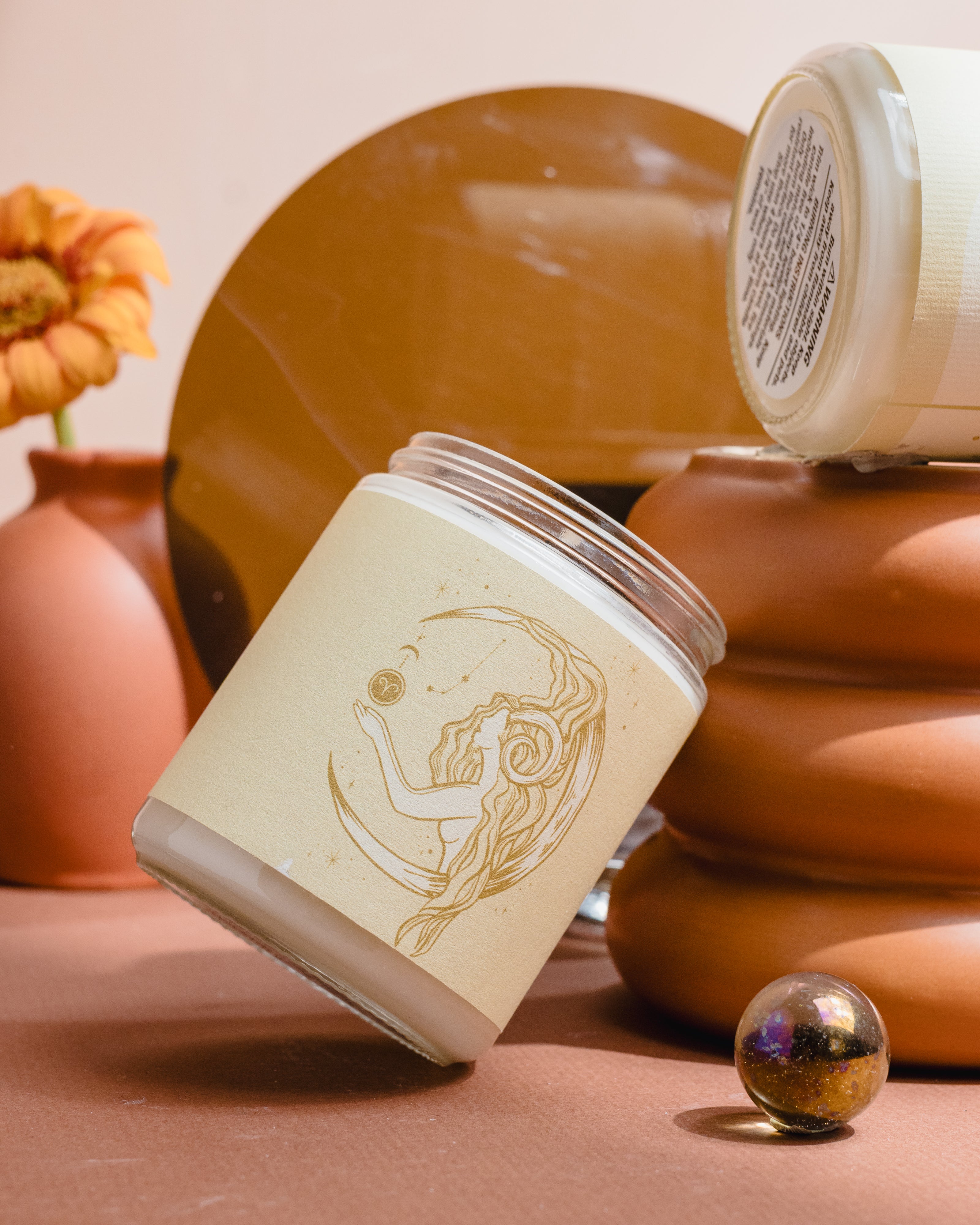 Hand-poured soy wax Aries candle from Wax Crescent, displayed with earthy decor and a single orange flower