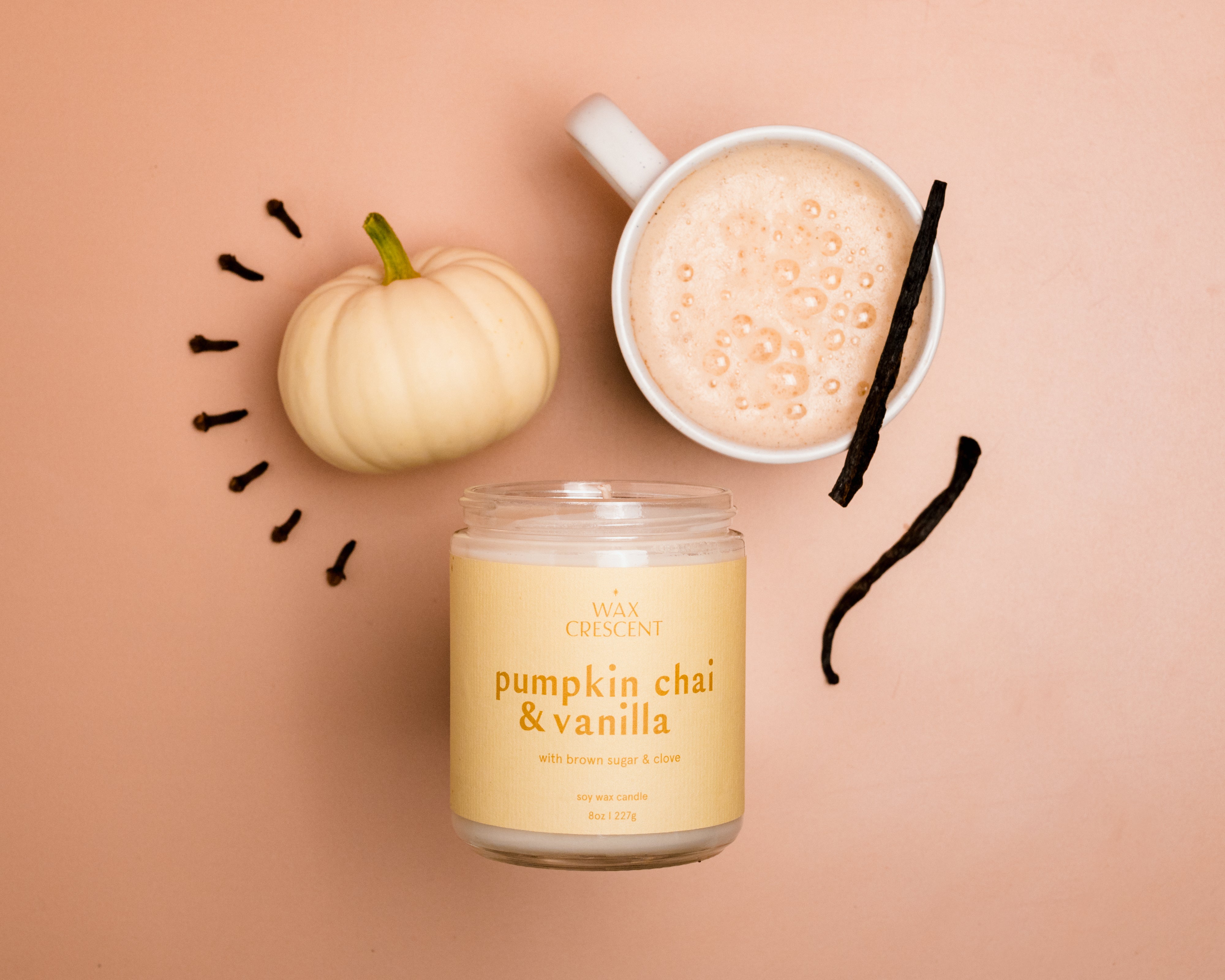 Pumpkin Chai & Vanilla soy wax candle by Wax Crescent, styled with a creamy chai latte, mini white pumpkin, vanilla bean, and cloves, evoking cozy autumn vibes.