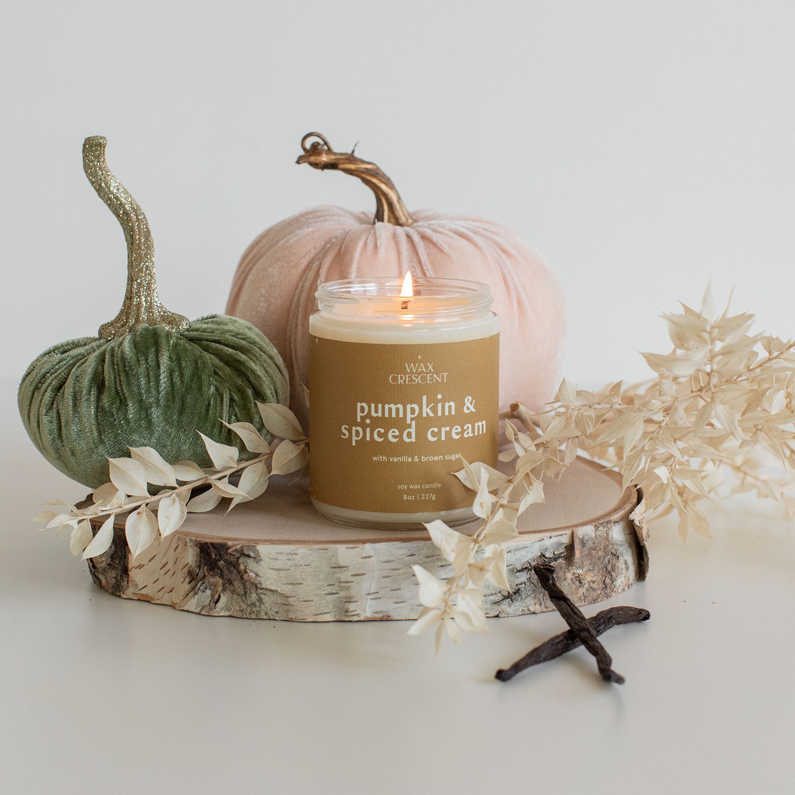 Pumpkin & Spiced Cream candle styled with autumn decor, including pumpkins and wooden accents, embodying the cozy essence of fall with spiced cream and vanilla