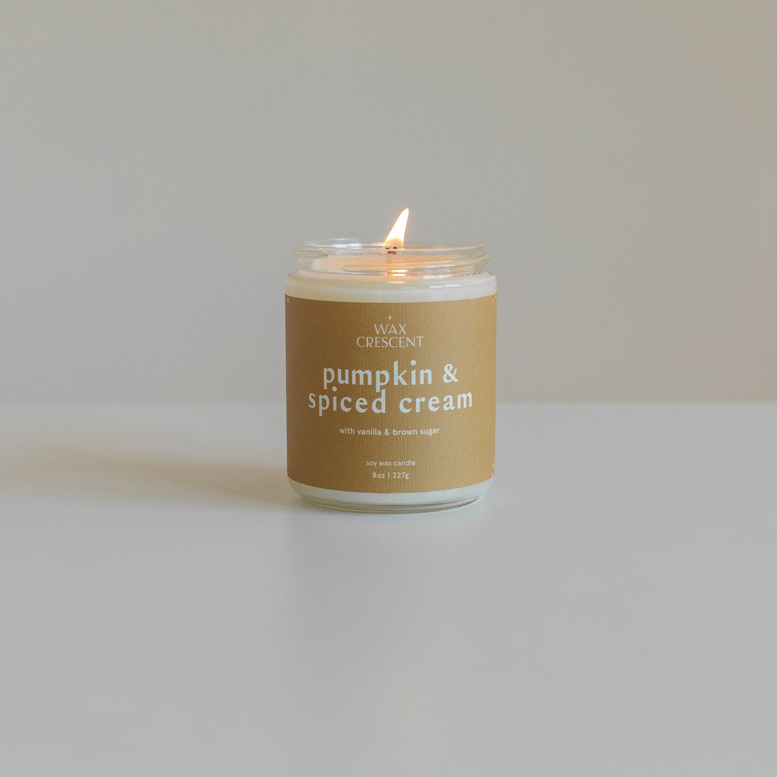 Pumpkin & Spiced Cream soy candle by Wax Crescent, burning with a cozy glow, featuring warm notes of pumpkin, vanilla, and cinnamon for a perfect fall ambiance