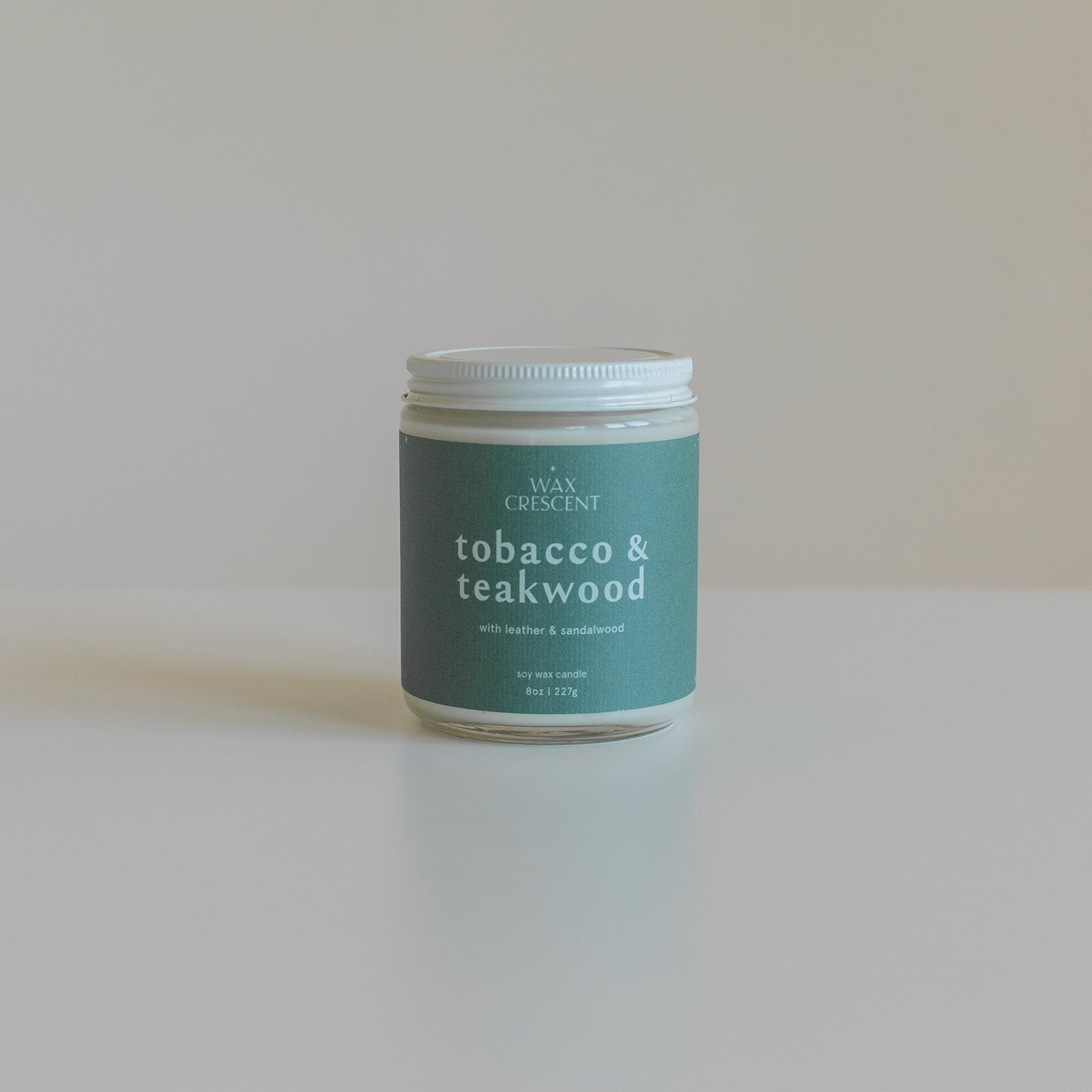 Tobacco & Teakwood candle with a white lid against a clean white background, showcasing its minimalist design and elegant branding