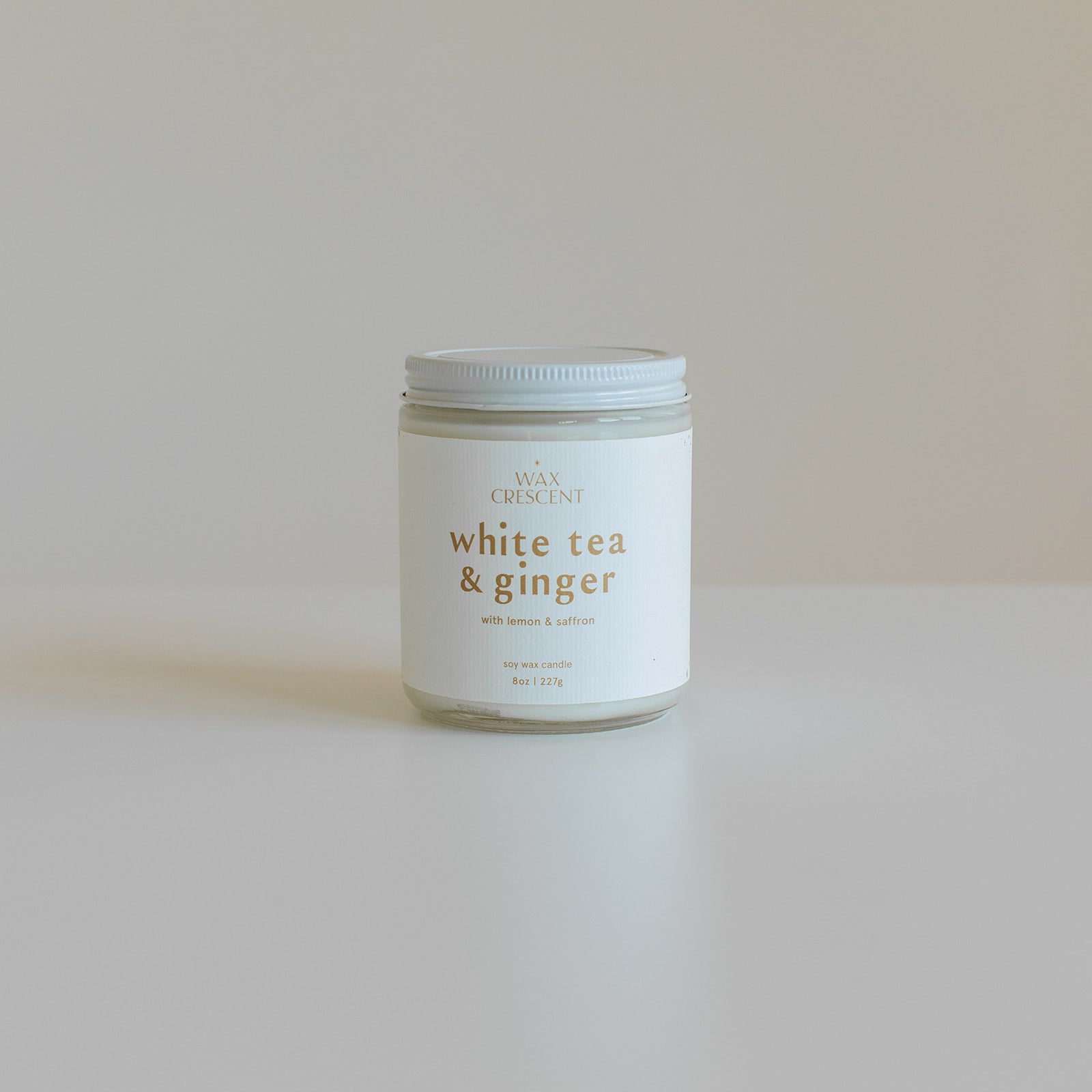 White Tea & Ginger candle on a white background with its lid beside it. This luxury soy wax candle features notes of mandarin, lemon, bergamot, and ginger, creating a sophisticated aroma.