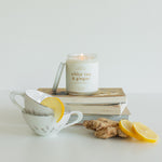 White Tea & Ginger candle surrounded by fresh ginger and lemon slices. This luxurious candle features aromatic notes of mandarin, lemon, bergamot, ginger, jasmine, white tea, and saffron, creating an inviting and sophisticated ambiance