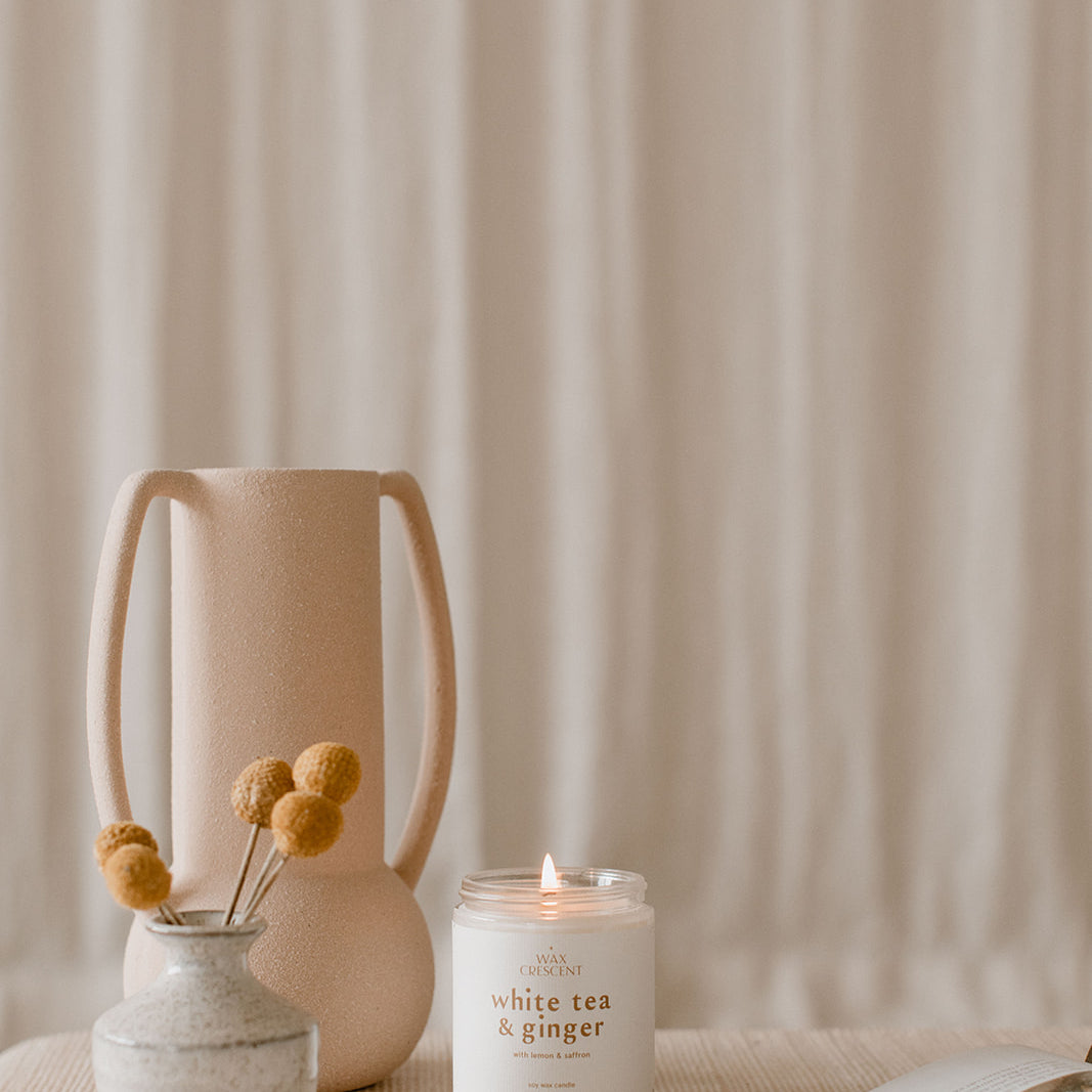 A lit soy wax candle from Wax Crescent displayed in a serene, minimalist setting with soft neutral decor, evoking a calm and relaxing atmosphere, perfect for self-care moments.