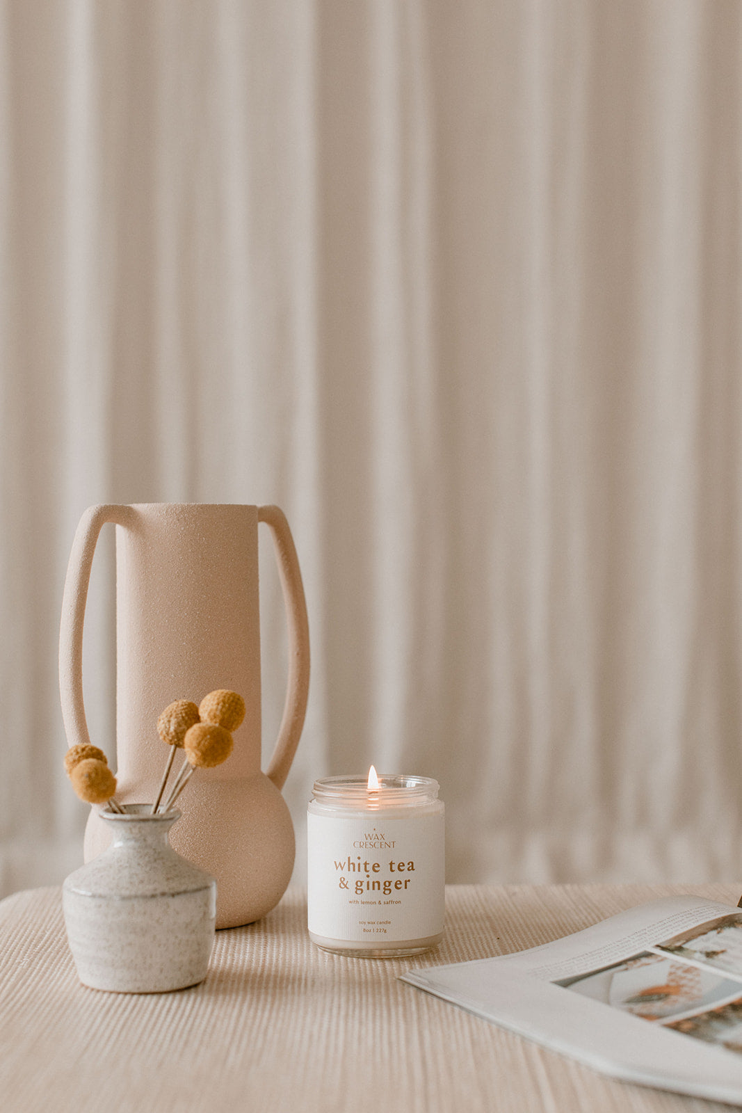 A lit soy wax candle from Wax Crescent displayed in a serene, minimalist setting with soft neutral decor, evoking a calm and relaxing atmosphere, perfect for self-care moments.