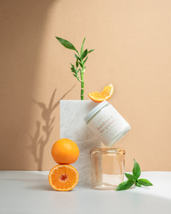 Wax Crescent Bamboo & Bergamot candle styled with fresh oranges, bamboo stems, and natural greenery against a minimalist beige backdrop. A refreshing, spa-like ambiance