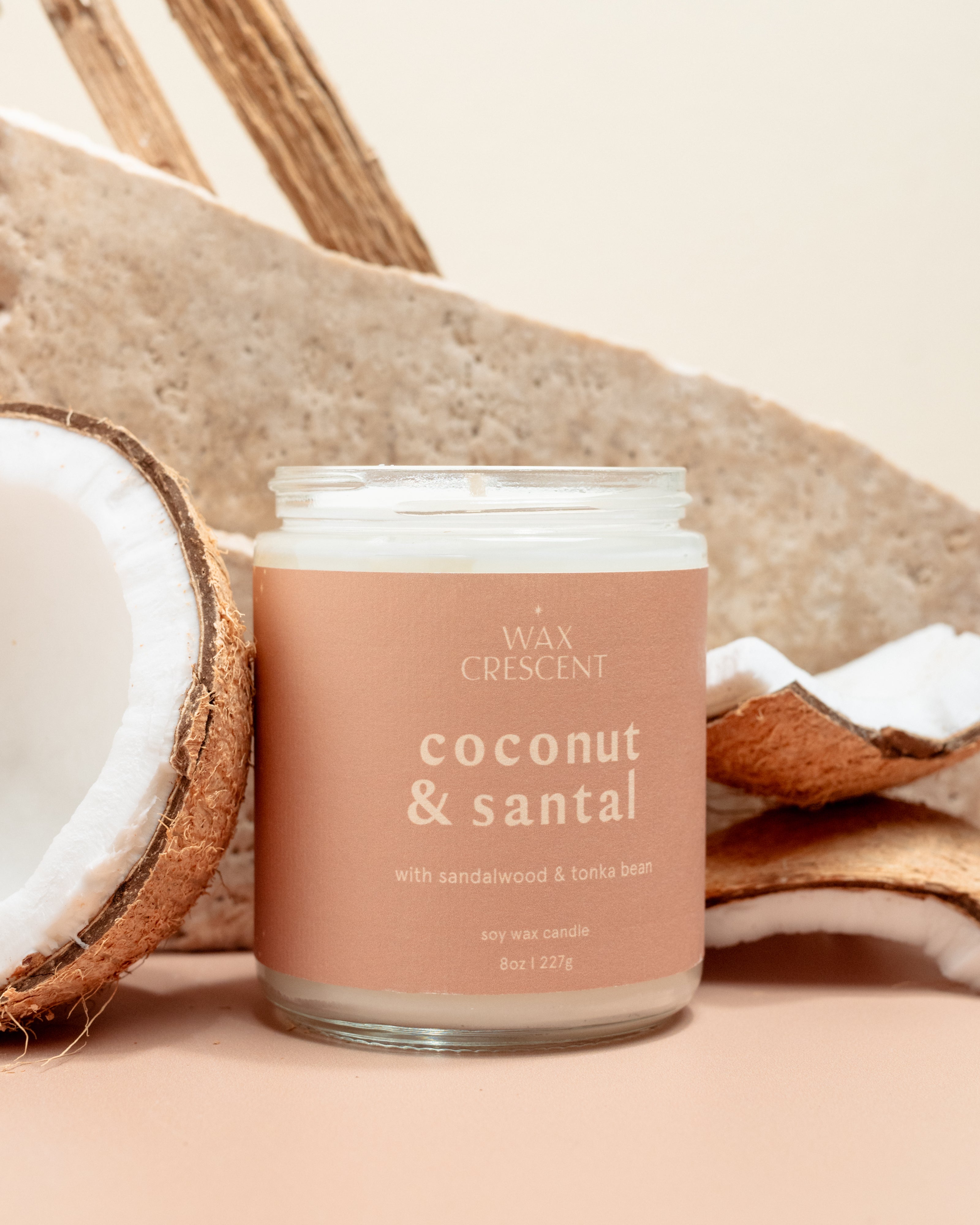 Wax Crescent Coconut & Santal soy candle paired with fresh coconut and wooden elements, creating a serene and earthy aesthetic against a light, minimal background
