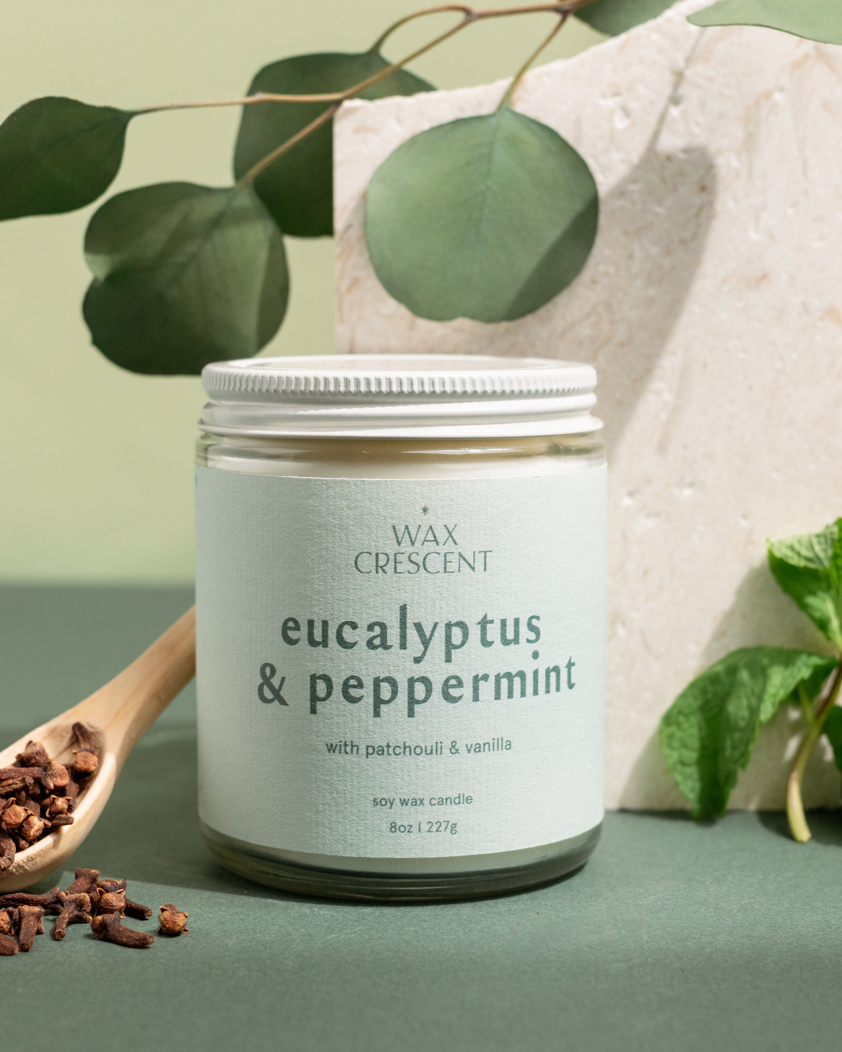 Hand-poured Eucalyptus & Peppermint candles from Wax Crescent, photographed with eucalyptus leaves and pine — a fresh, festive scent that captures the spirit of the season