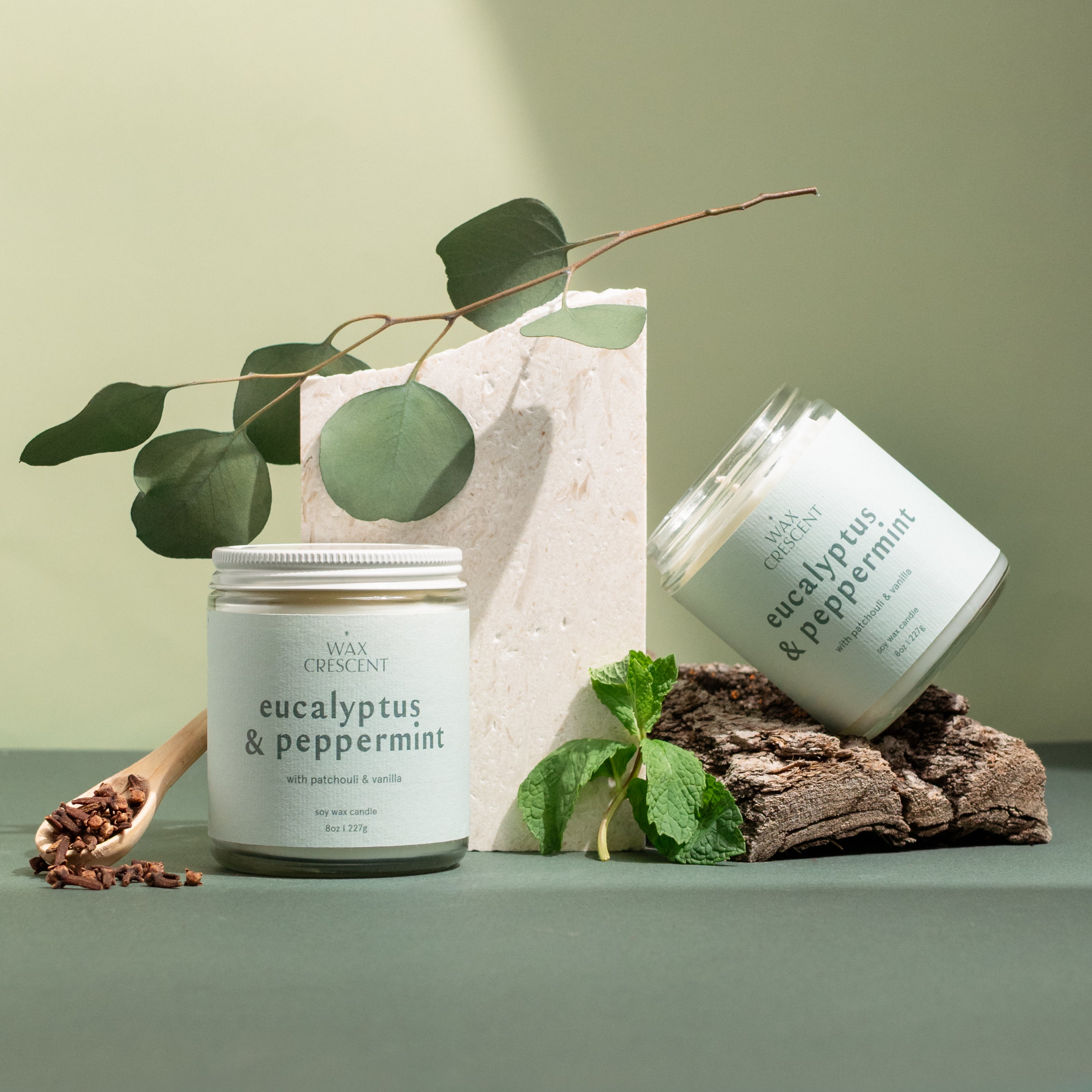 Two Eucalyptus & Peppermint soy candles styled with winter greenery and pine — a clean, refreshing scent handcrafted by Wax Crescent for cozy holiday moments