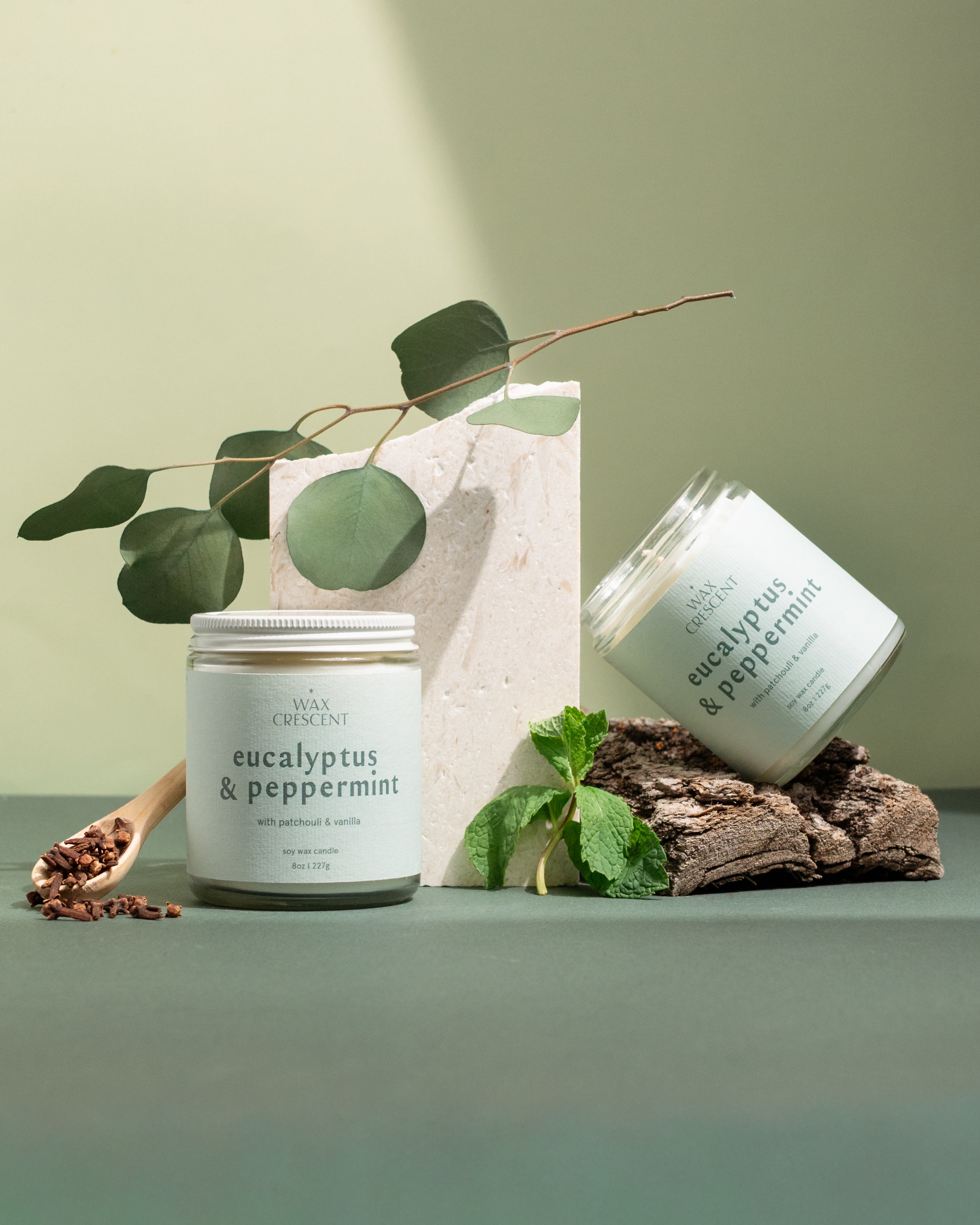 Two Eucalyptus & Peppermint soy candles styled with winter greenery and pine — a clean, refreshing scent handcrafted by Wax Crescent for cozy holiday moments
