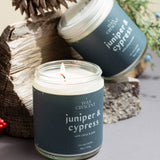 Pair of Juniper & Cypress candles with natural decorative elements on a neutral background — small-batch soy candles from Wax Crescent that bring fresh evergreen calm to any space