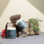 Two Juniper & Cypress soy candles surrounded by evergreen sprigs and pine — clean, woodsy fragrance handcrafted by Wax Crescent to evoke the stillness of winter forests