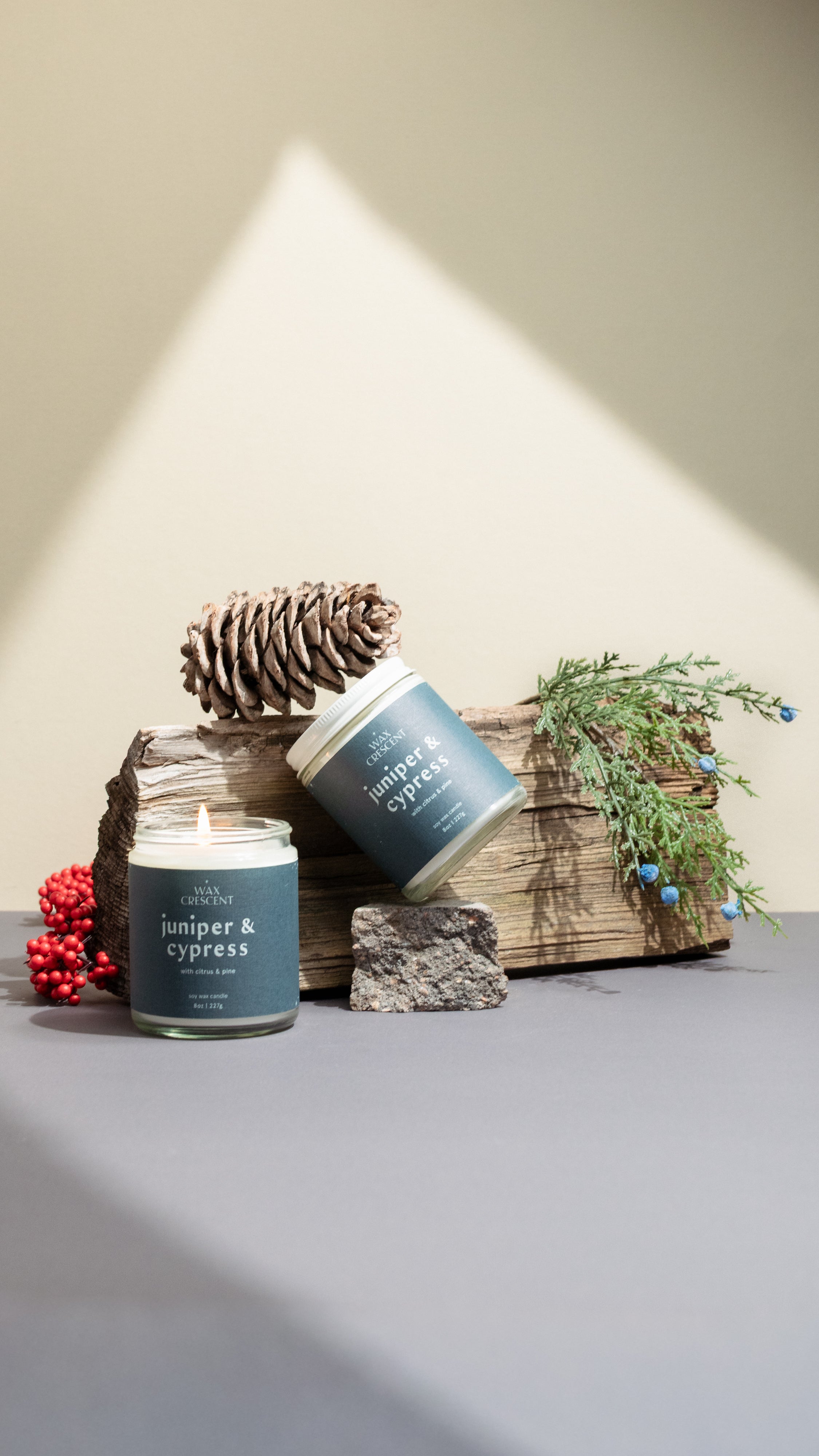 Two Juniper & Cypress soy candles surrounded by evergreen sprigs and pine — clean, woodsy fragrance handcrafted by Wax Crescent to evoke the stillness of winter forests