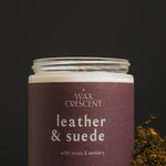 Close-up of Leather & Suede soy candle with rich notes of leather, clove, and cedar, styled with moss for a rugged look