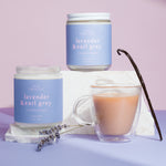 Two lavender-scented candles and a cup of tea on a purple surface with a light purple background.