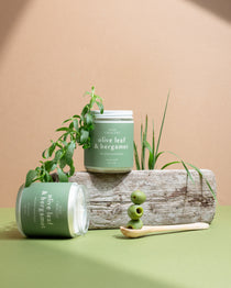 Two Olive Leaf & Bergamot soy candles with olive branches and fresh olives on a beige background — luxury hand-poured candles by Wax Crescent inspired by Mediterranean calm and golden light.