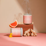 Pink candle labeled 'Red Ginger & Cardamom' with decorative elements on a pink surface.