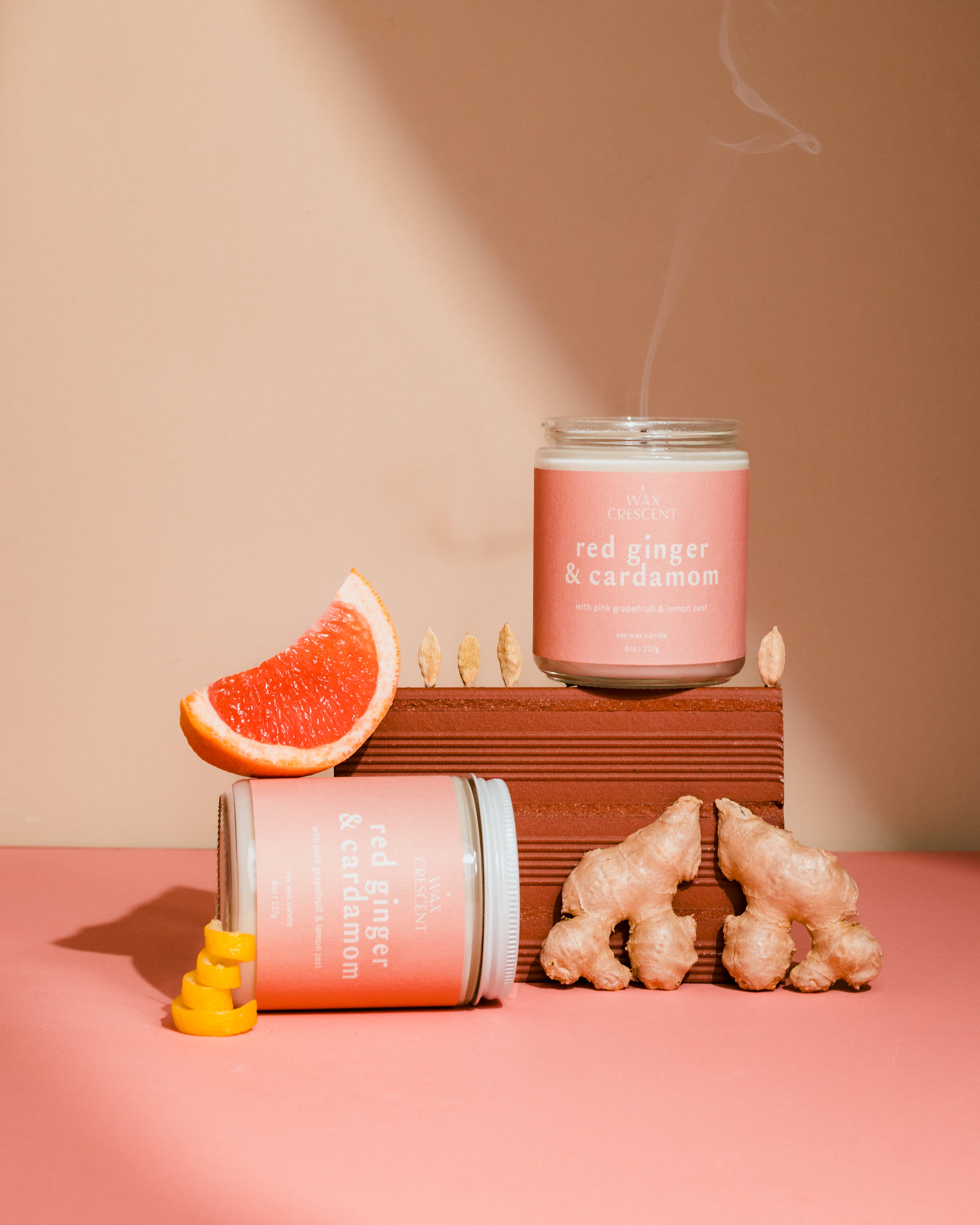 Candle with 'Red Ginger & Cardamom' scent on a pink background