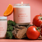 Tomato & Vetiver luxury soy candle styled with fresh tomatoes and citrus on a pink background for a modern summer fragrance campaign.