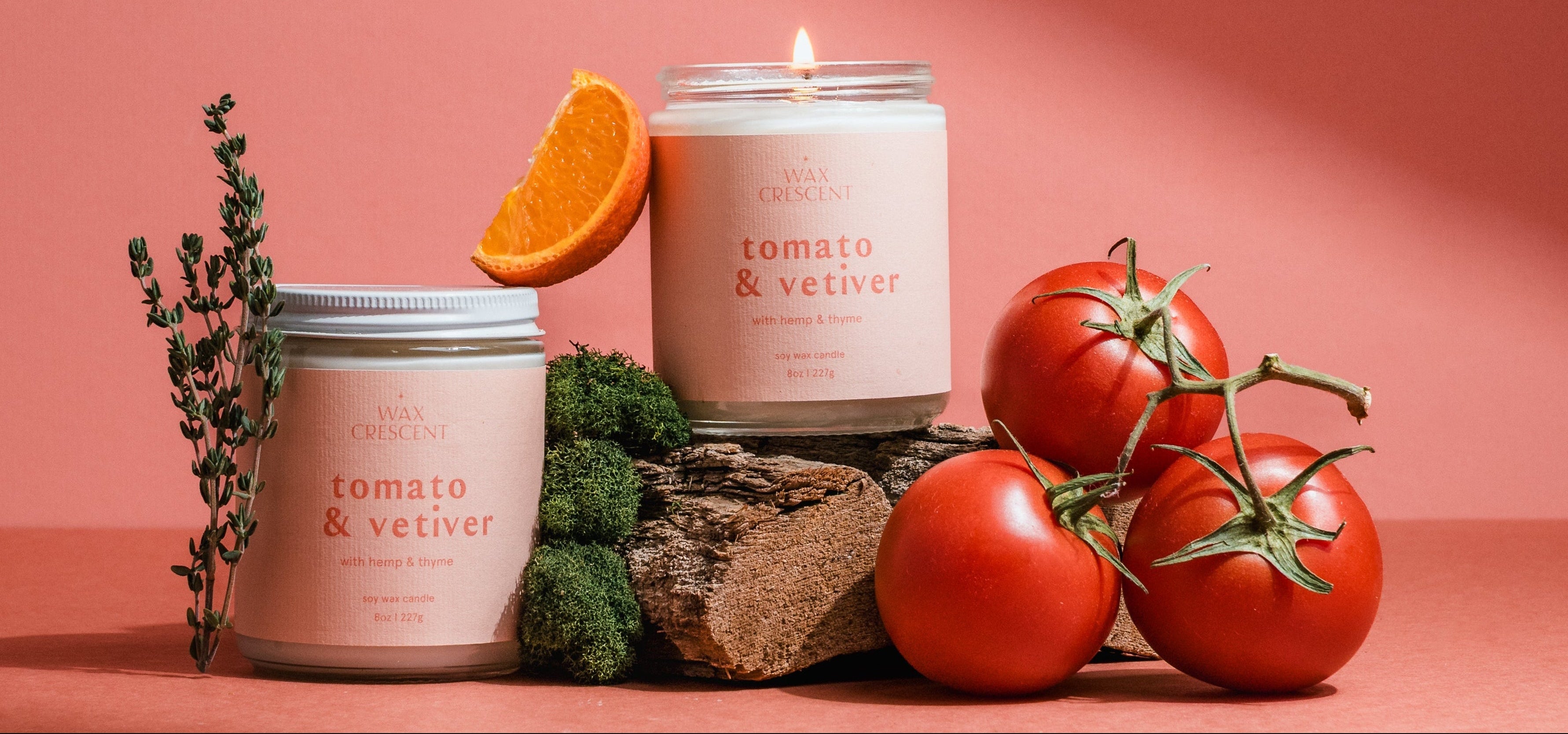 Tomato & Vetiver luxury soy candle styled with fresh tomatoes and citrus on a pink background for a modern summer fragrance campaign.