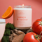 Modern luxury Tomato & Vetiver candle featuring fresh tomato vine inspiration with citrus and produce styling on a soft pink background.