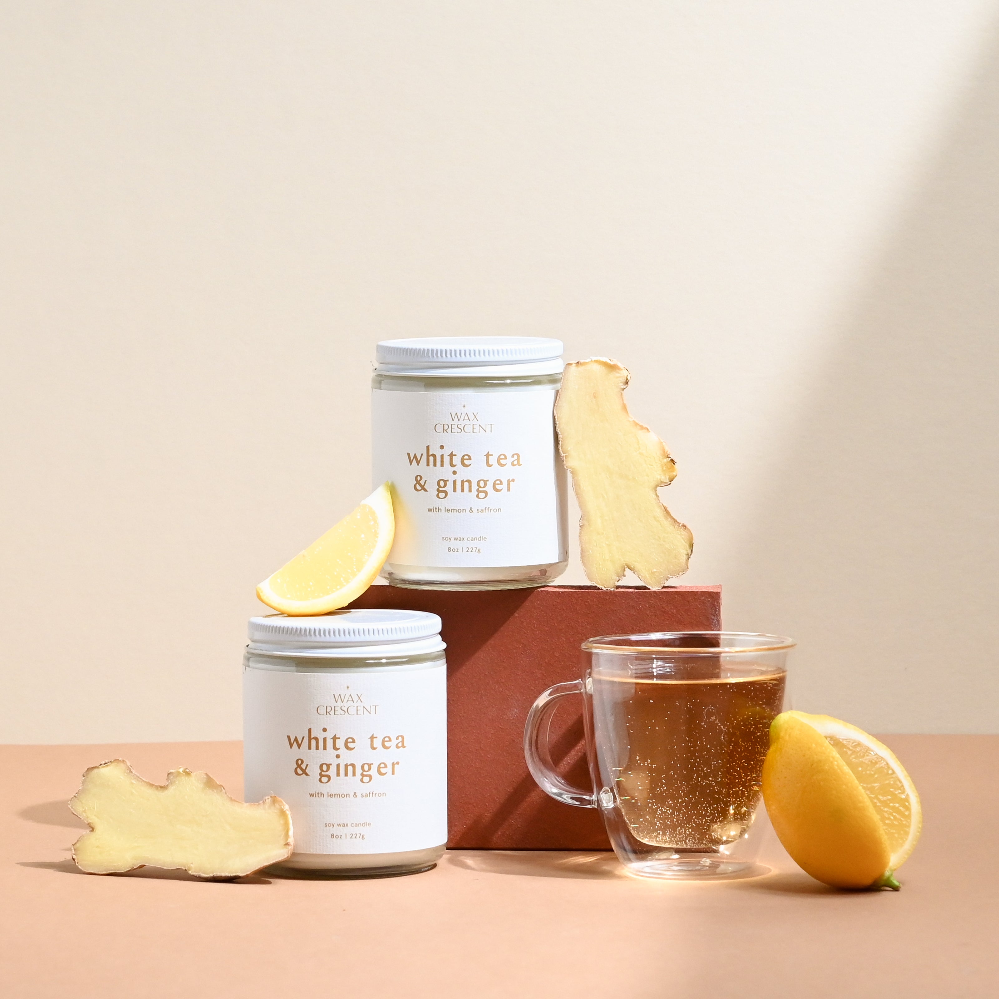 Wax Crescent White Tea & Ginger soy candle styled with fresh lemon, ginger root, and a glass of tea. A luxurious, eco-friendly candle for a calming ambiance