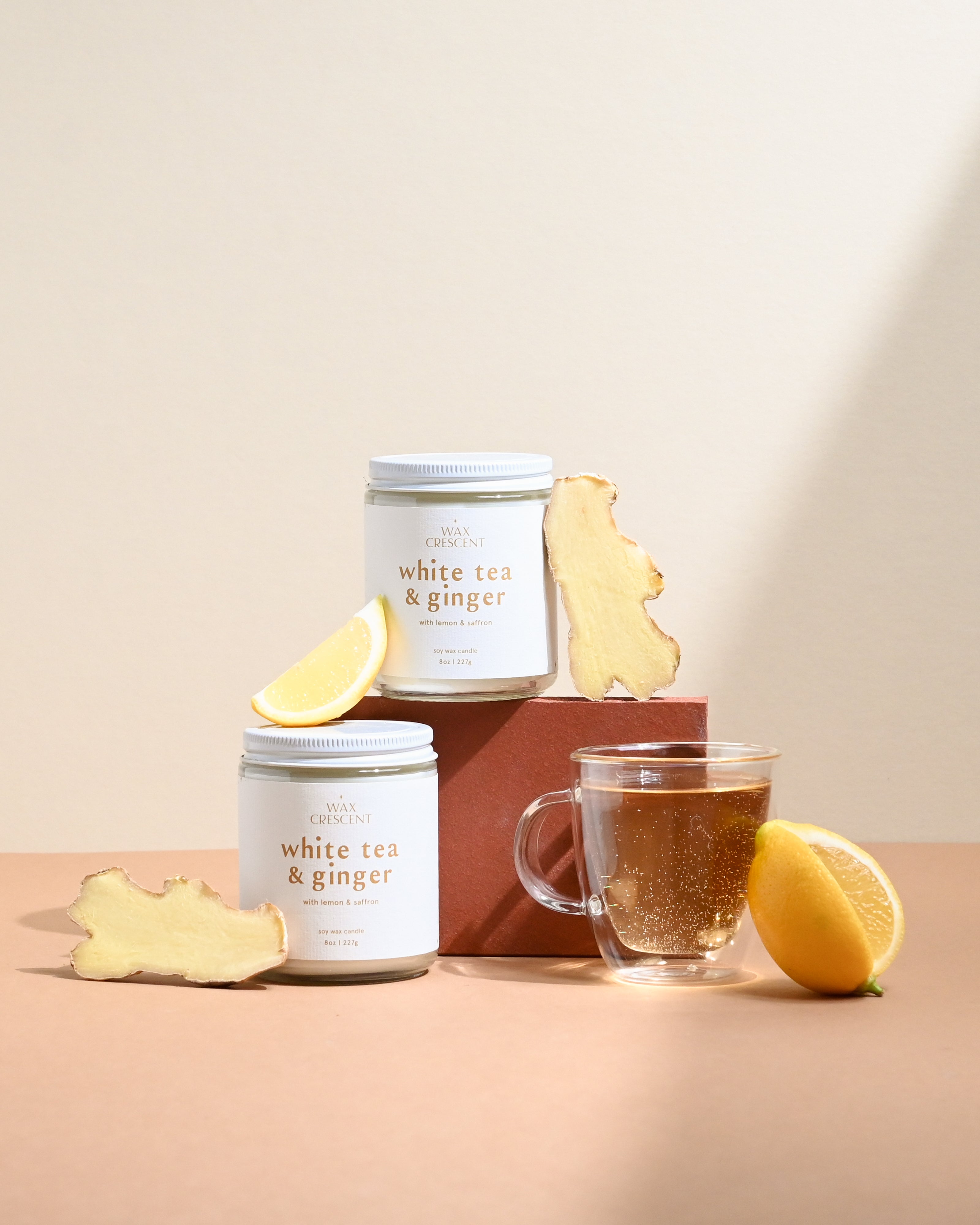 Wax Crescent White Tea & Ginger soy candle styled with fresh lemon, ginger root, and a glass of tea. A luxurious, eco-friendly candle for a calming ambiance