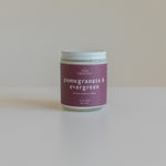 Pomegranate & Evergreen soy candle with a minimalist design, featuring a berry-colored label, hand-poured with non-toxic fragrance oils