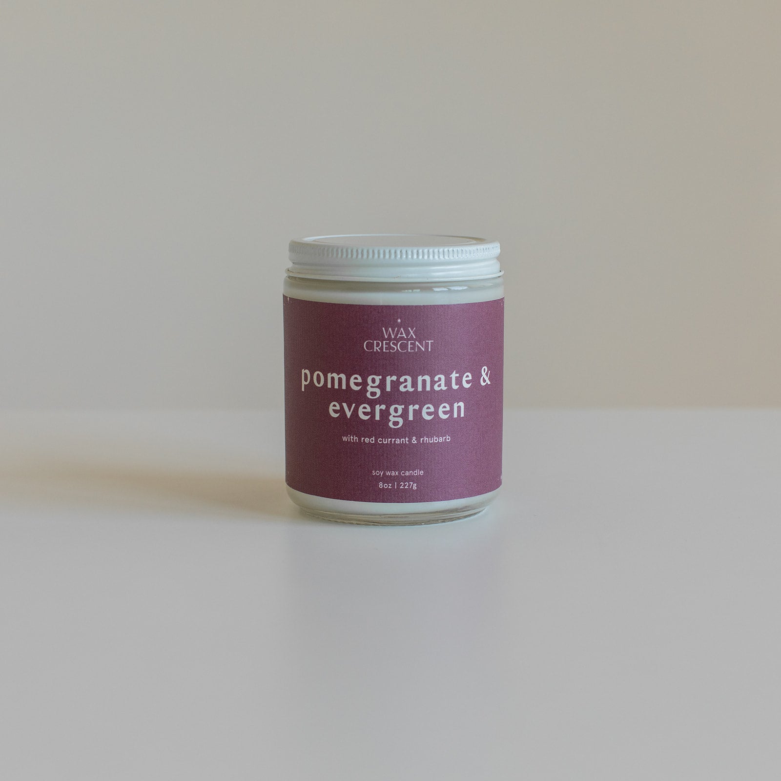 Pomegranate & Evergreen soy candle with a minimalist design, featuring a berry-colored label, hand-poured with non-toxic fragrance oils